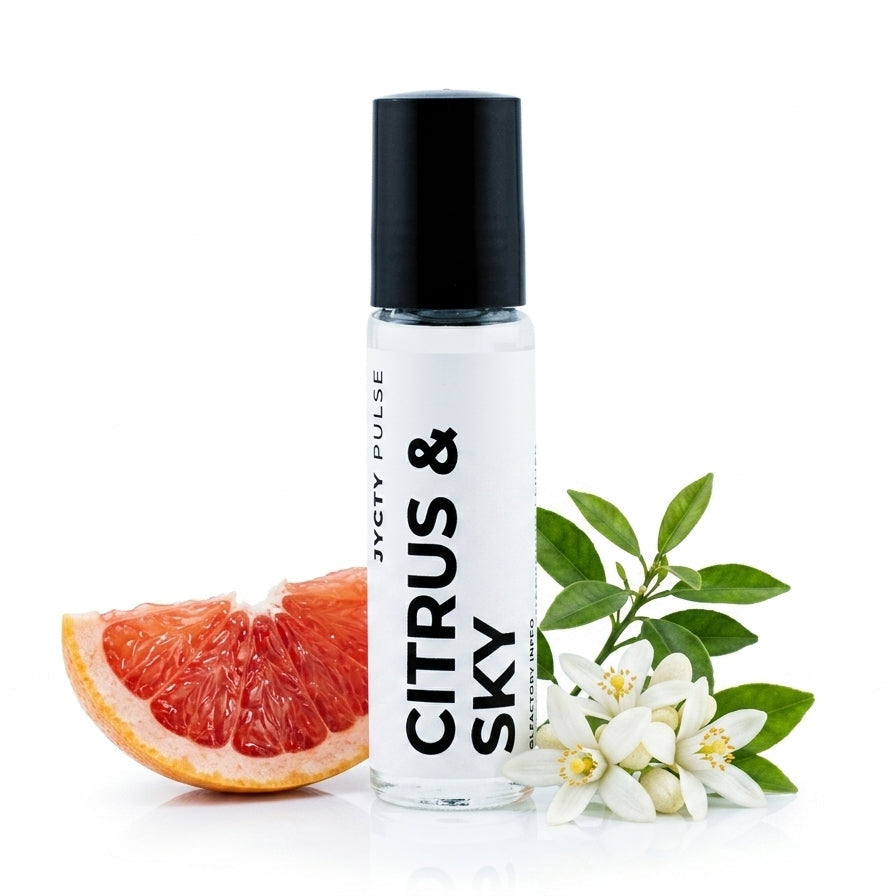 A clear cylindrical roller bottle with a black cap and a white label reading 'CITRUS & SKY' and 'JCYTY PULSE', styled with a grapefruit slice, white citrus blossoms, and green leaves on a white background.
