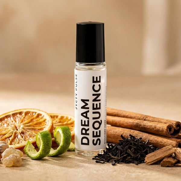 Perfume oil Roll-on bottle labeled 'Dream Sequence' with cinnamon sticks, lime slices, and dried fruits on a wooden surface.