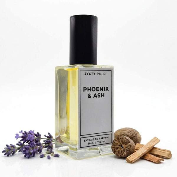 A 50ml bottle of JycTy Pulse Phoenix & Ash Extrait de Parfum, featuring a clear glass bottle with a black cap and a white label, styled with lavender sprigs, a nutmeg, and cinnamon sticks on a white background.