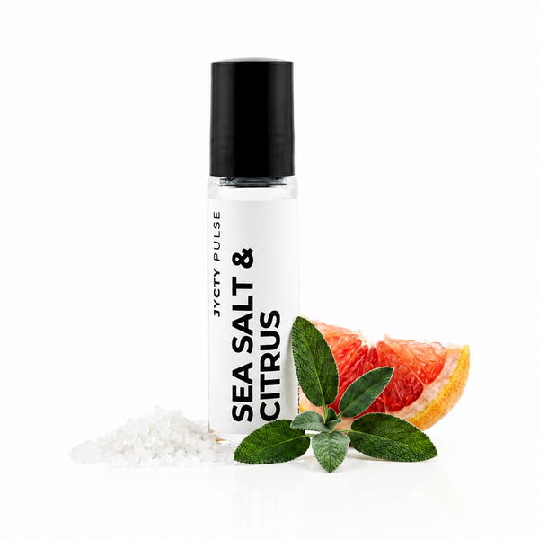 A clear cylindrical bottle with a black cap labeled 'SEA SALT & CITRUS' by JYCTY PULSE, shown on a white background with coarse white salt crystals, green leaves, and a grapefruit slice beside it.