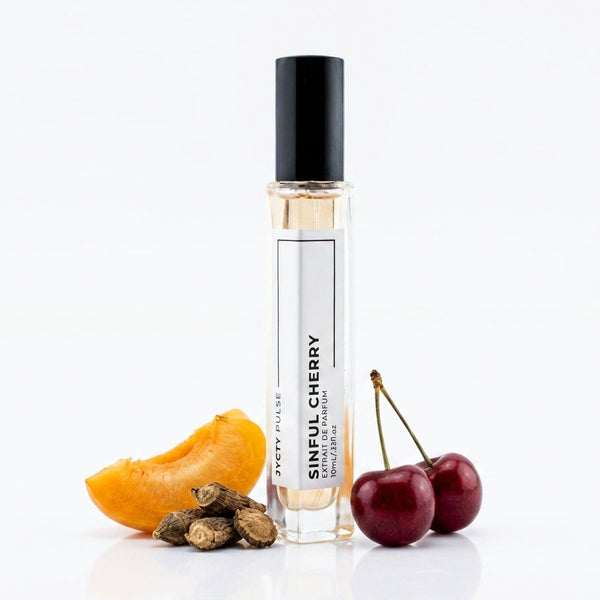 A clear glass roll-on perfume bottle labeled 'SINFUL CHERRY' with a black cap, styled on a white background with a cherry slice, cherries, and dried cherry pits.