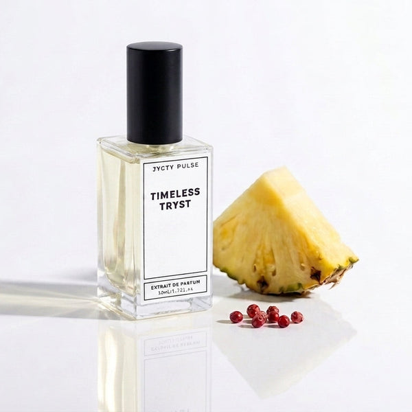 A clear 50ml glass perfume bottle with a black cap and a white label reading 'TIMELESS TRYST' shown on a white reflective surface beside a pineapple wedge and a few red berries.