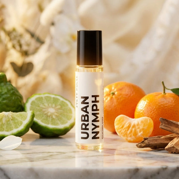 Roller bottle labeled 'Urban Nymph' surrounded by fruits and flowers on a marble surface.